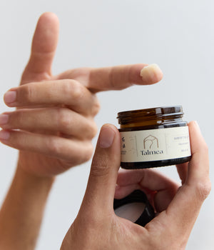 Hand entnimmt Talmea Sheep Tallow Creme aus geöffnetem Glas